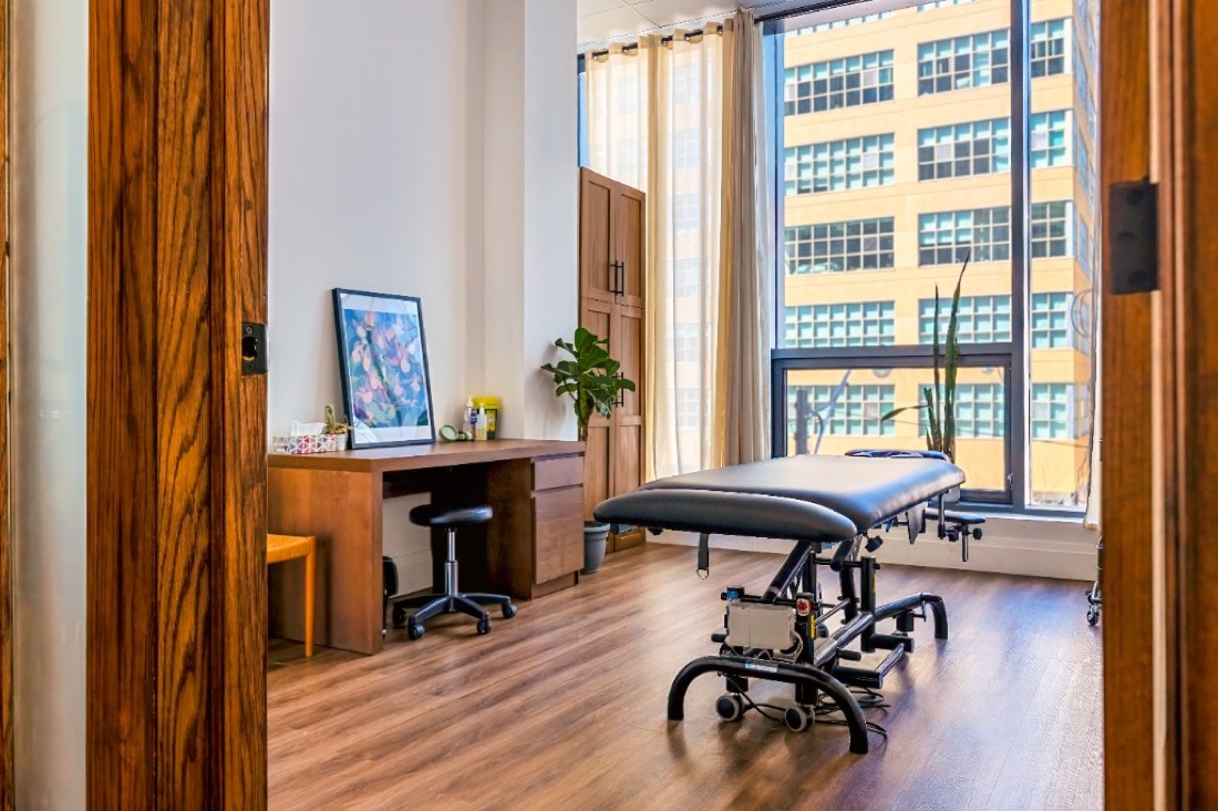 Recreo Rehab treatment room with massage table, natural light, and city views
